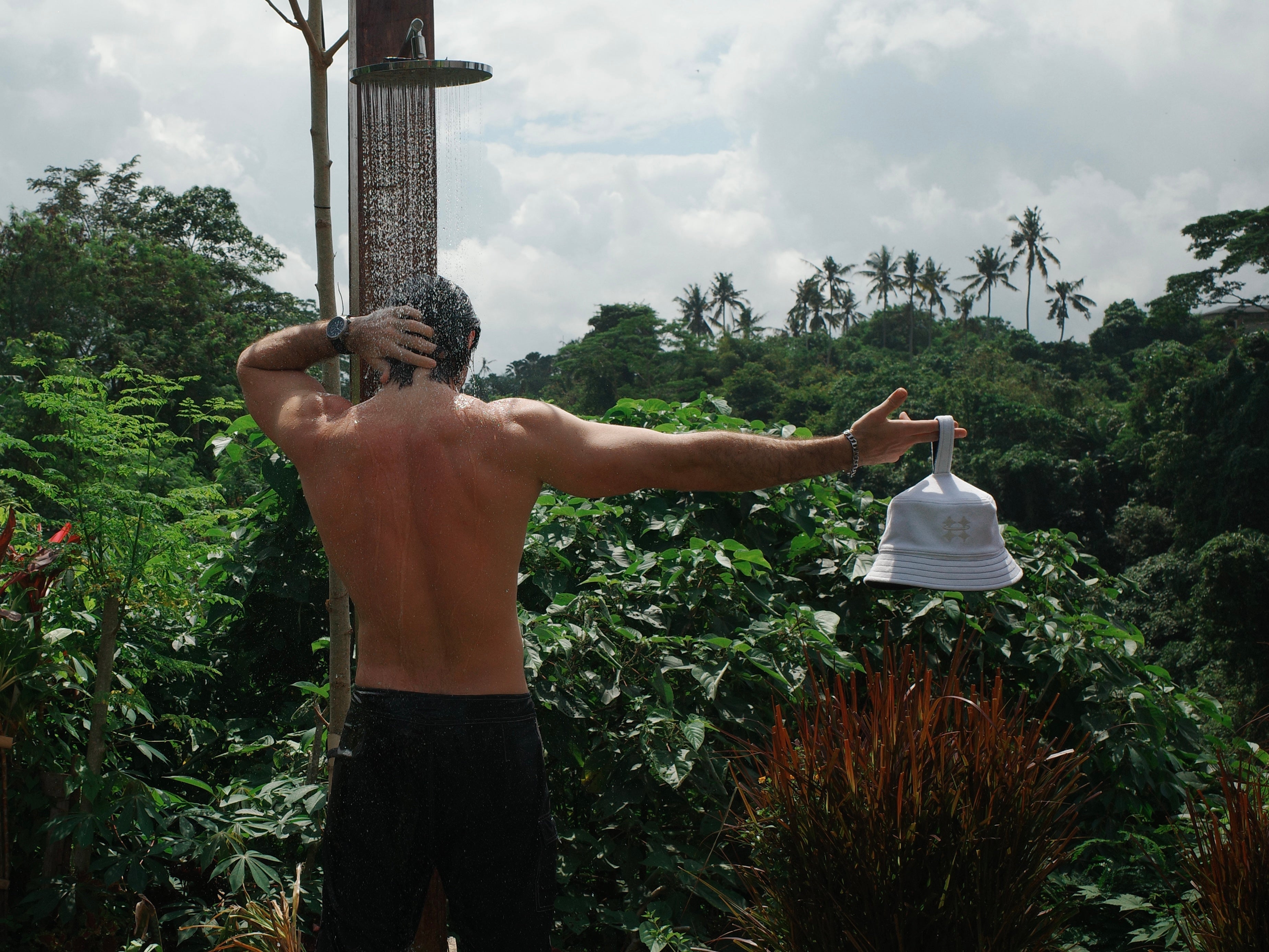 man showing wearing black shorts and holding a white Halo sauna hat