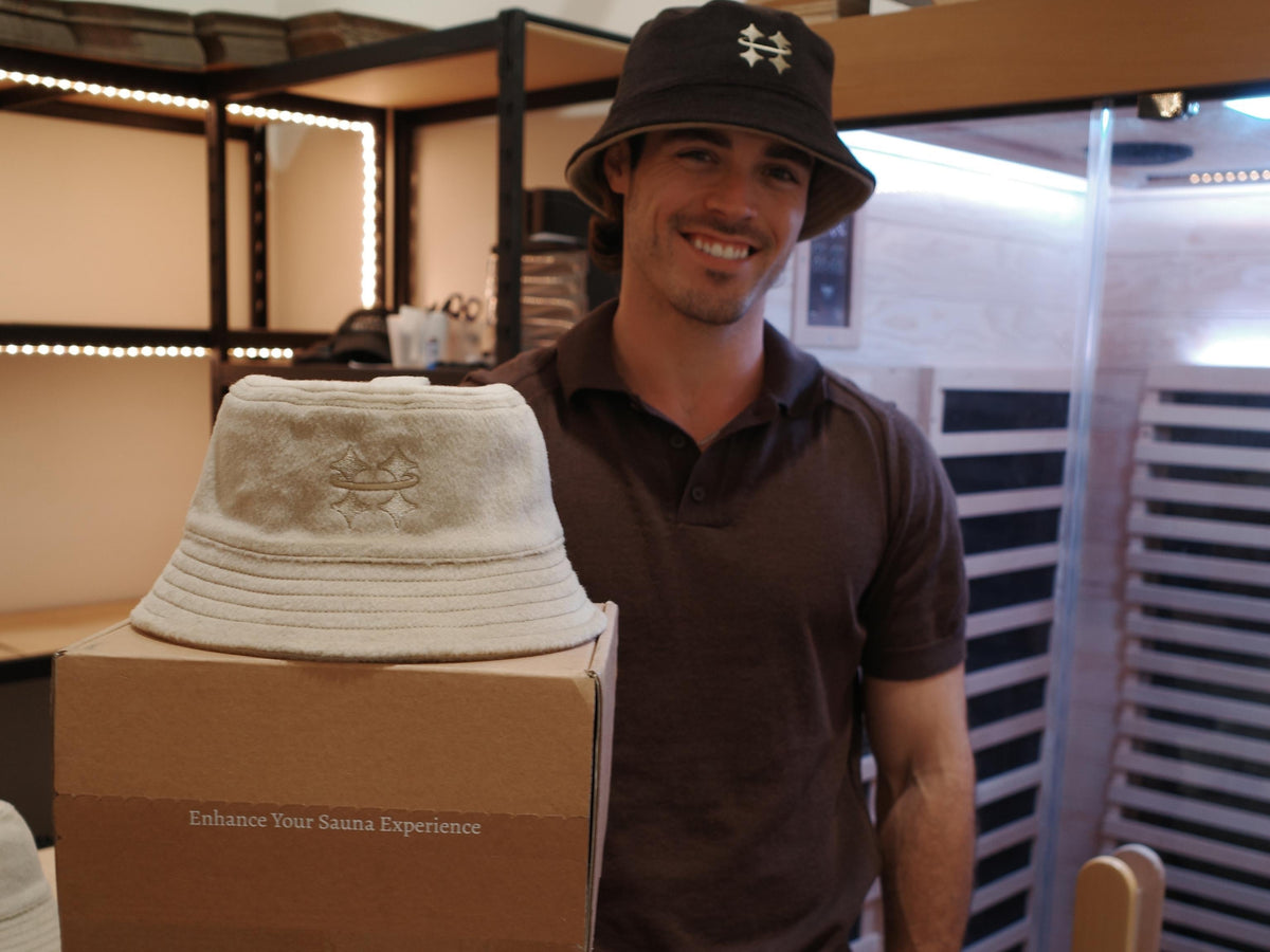 Man holding a box with a Halo sauna hat while wearing a brown Halo sauna hat